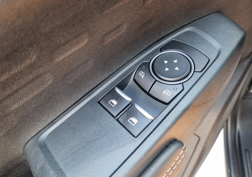 Gros plan sur les commandes de réglage des rétroviseurs et vitres côté conducteur du Ford Ranger blanc.