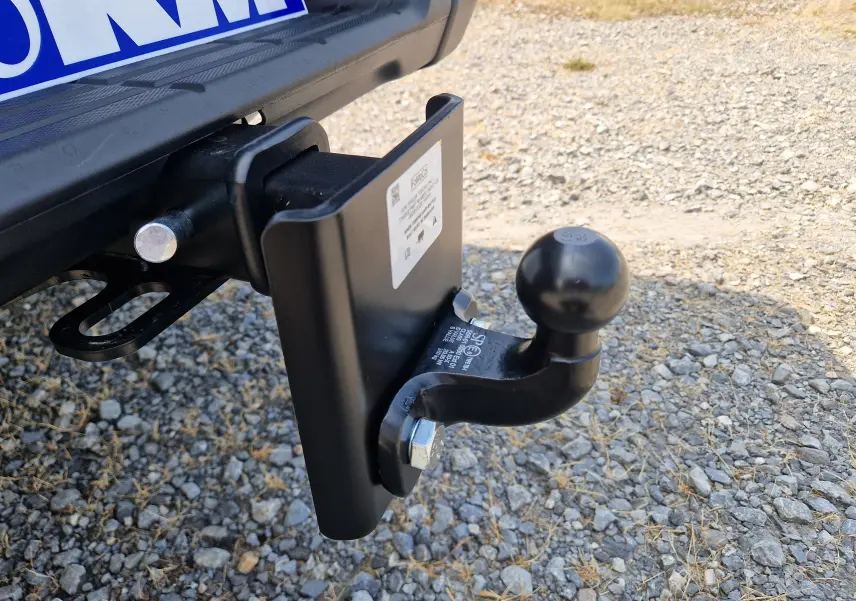 Gros plan sur l'attelage noir fixé à l'arrière du Ford Ranger Super Cabine blanc, sur un sol gravillonné.