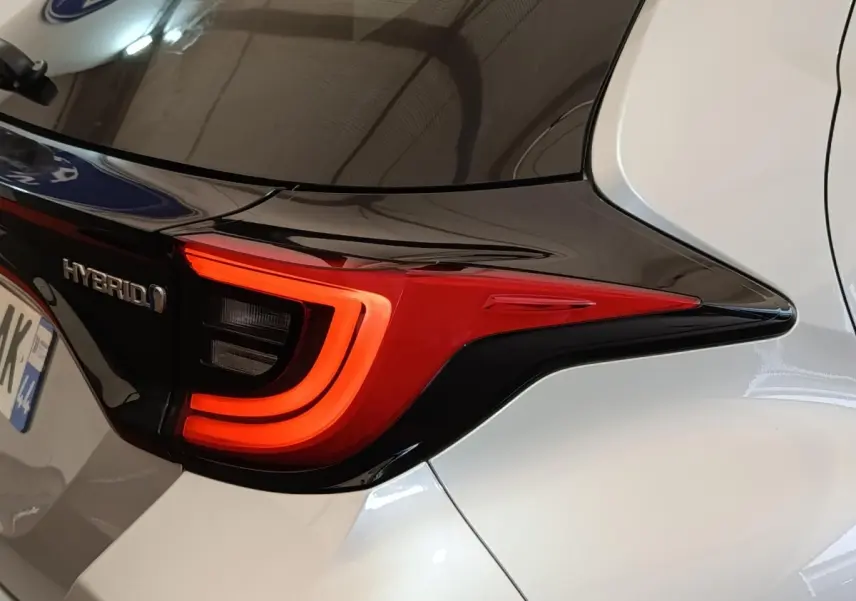 Gros plan sur le feu arrière droit rouge et noir de la Toyota Yaris hybride gris clair 2023, avec logo Hybrid visible.