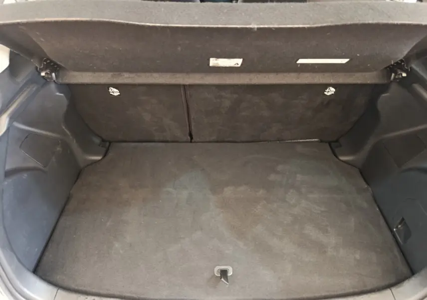 Coffre ouvert de la Toyota Yaris Hybride 116h Design gris clair, montrant un espace de chargement propre et vide.