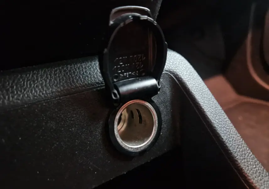Prise allume-cigare ouverte sur la console intérieure noire du Renault Kangoo Van blanc 2023, vue rapprochée.