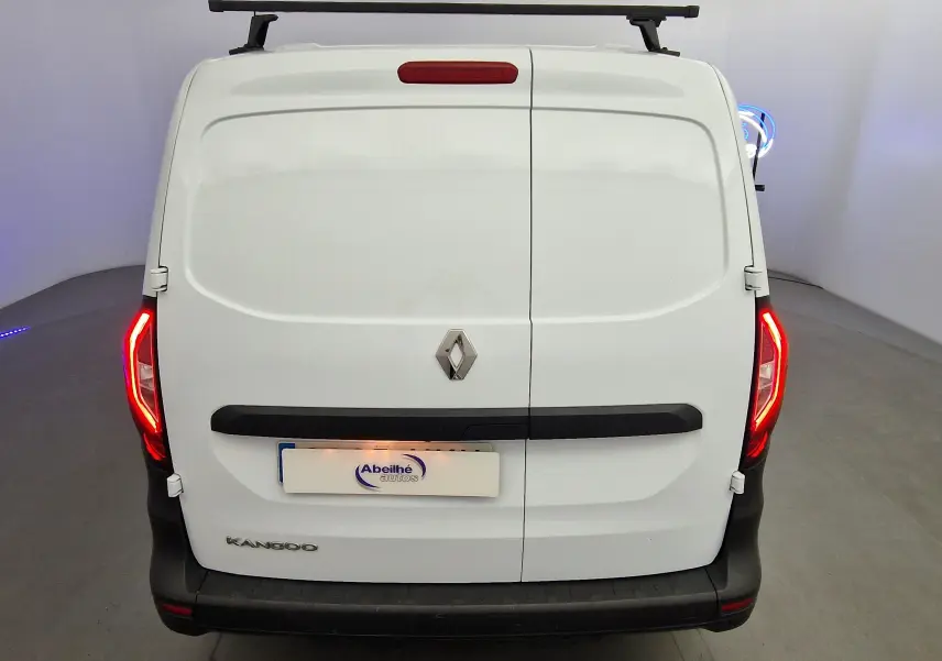 Vue arrière d’un Renault Kangoo blanc 2023 avec feux allumés et barre de toit noire visible en studio.