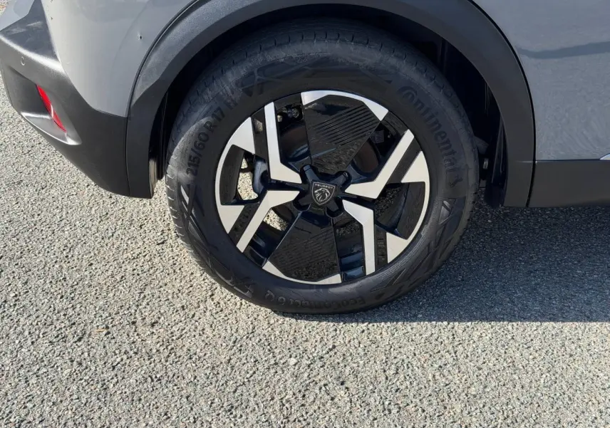 Gros plan sur la roue arrière droite du Peugeot e-2008 gris Artense avec jante alu noire et argentée.