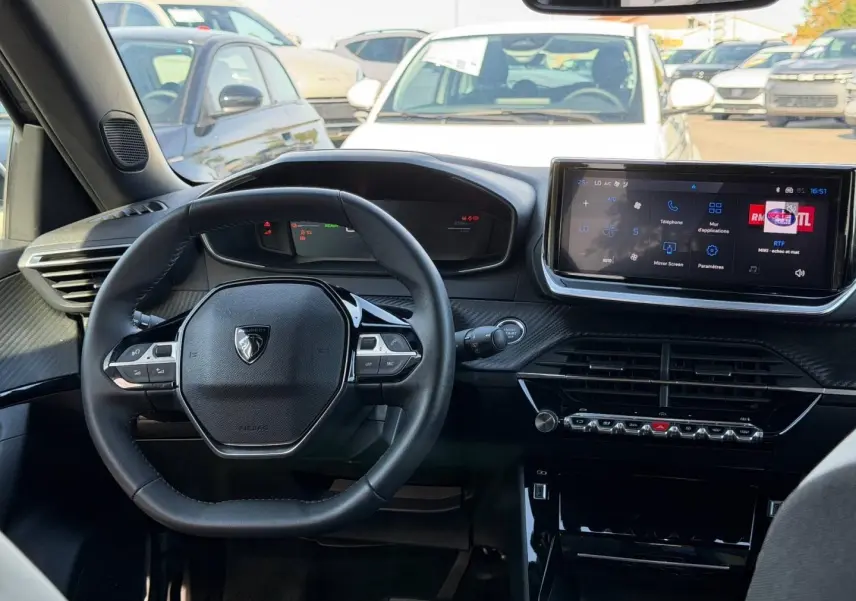 Intérieur de la Peugeot e-2008 2025 vu de face, volant multifonction et écran tactile central allumé.