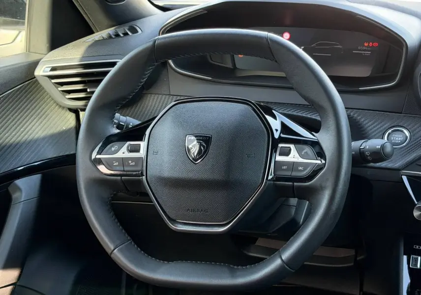 Volant multifonction noir de la Peugeot e-2008 2025, vue de face avec tableau de bord numérique en arrière-plan.