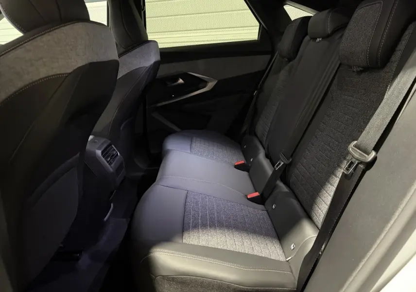 Vue intérieure arrière droite des sièges arrière en tissu et cuir gris du Peugeot 3008 blanc hybride 2026.