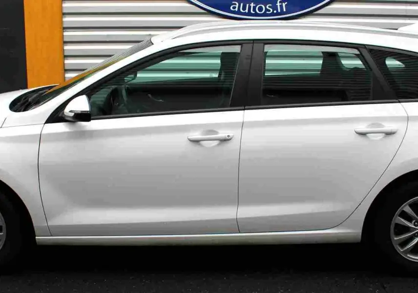 Profil côté gauche d'une Hyundai i30 SW 2022 blanche polaire, break compact avec jantes alliage et vitres teintées.