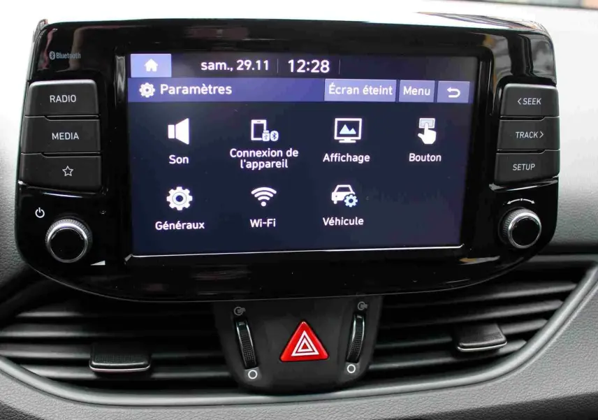 Écran tactile central de la Hyundai i30 SW blanc polaire 2022 affichant les paramètres multimédia et connectivité.