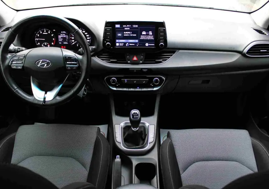 Vue intérieure frontale du tableau de bord et volant noir de la Hyundai i30 SW 2022 avec boîte manuelle et écran tactile central.