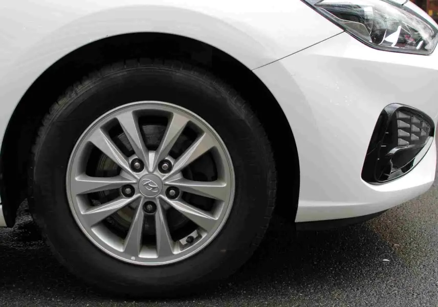 Gros plan sur la roue avant gauche et le pare-chocs blanc polaire d'une Hyundai i30 SW 2022 finition Comfort.