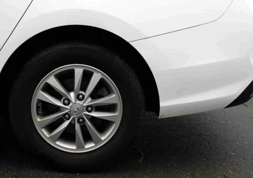 Gros plan sur la roue arrière gauche d'une Hyundai i30 SW blanche polaire avec jante alliage argentée.