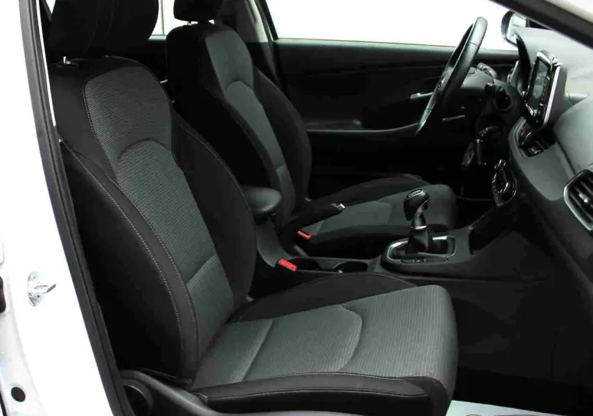 Vue intérieure côté conducteur de la Hyundai i30 SW 2022, sièges tissu gris noir et tableau de bord moderne.