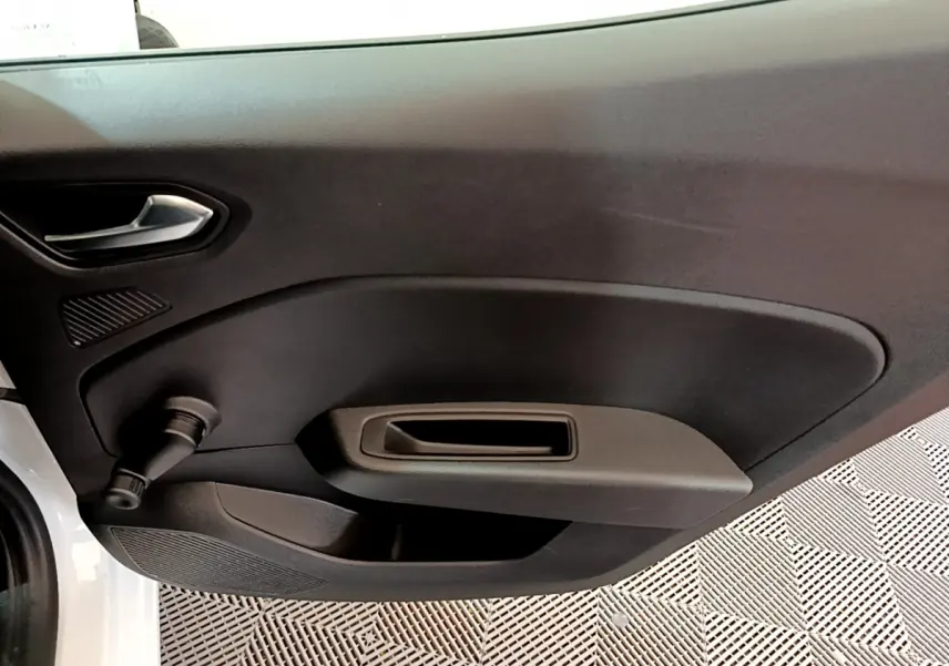 Vue rapprochée de la porte intérieure côté gauche d'une Renault Clio Business TCe 100 blanche, avec poignée et manivelle de vitre.