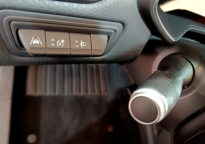 Gros plan sur les commandes d'assistance et réglage des phares à gauche du volant dans l'habitacle noir de la Renault Clio Business 2020.