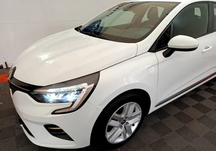 Renault Clio Business TCe 100 blanc vue 3/4 avant droit avec phares LED allumés et jantes alliage.