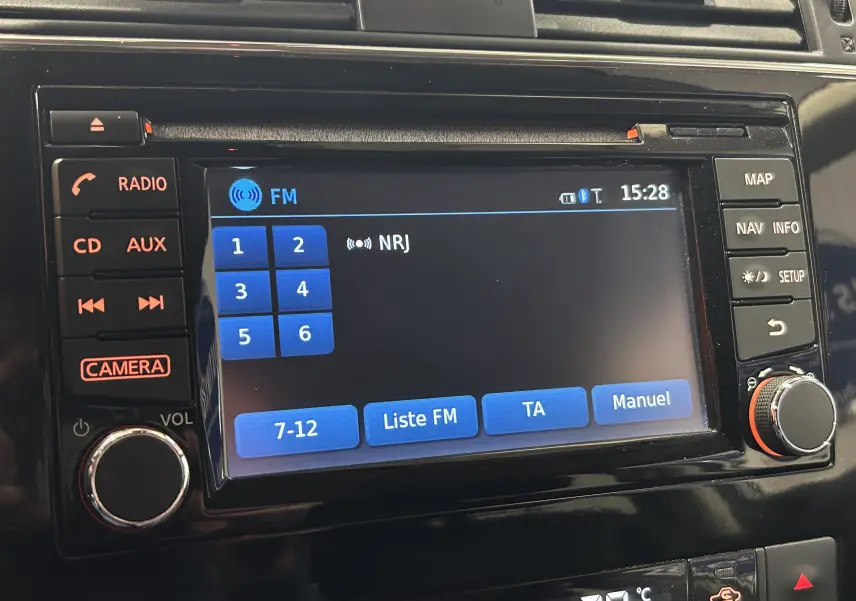 Gros plan sur l'écran multimédia noir de la Nissan Pulsar 2018 affichant la radio FM sur NRJ avec commandes tactiles et boutons physiques.