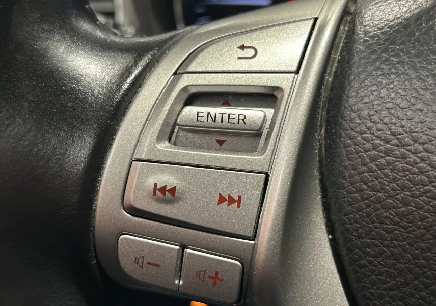 Gros plan sur les commandes argentées du volant en cuir noir du Nissan Pulsar gris, version 2018.