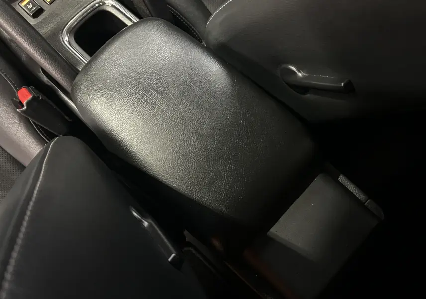 Gros plan sur l'accoudoir central en cuir noir de la Nissan Pulsar 1.5 dCi 110ch Ultimate, intérieur sombre.