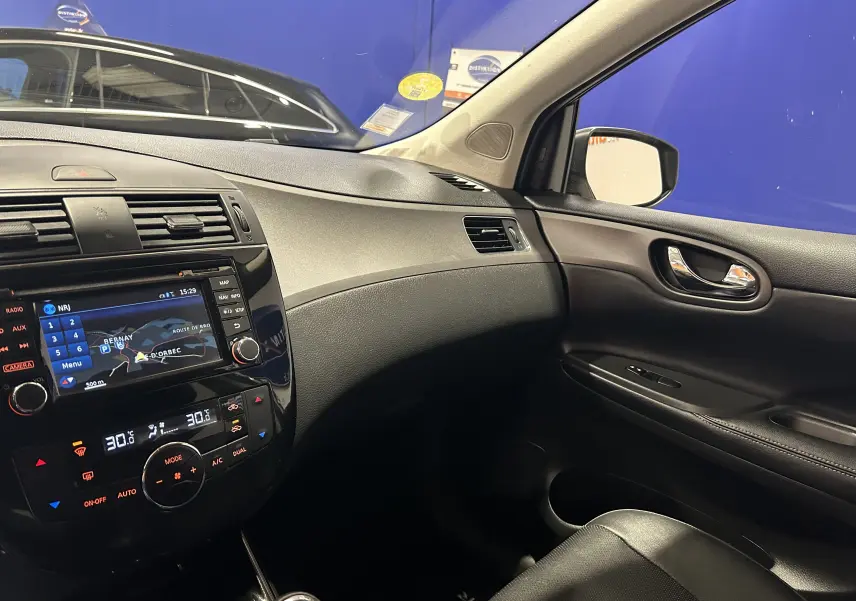 Vue intérieure côté passager de la Nissan Pulsar 1.5 dCi 110ch Ultimate avec tableau de bord noir et écran GPS allumé.