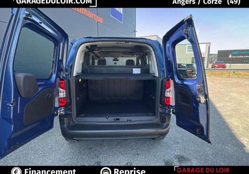 Vue arrière du Peugeot Rifter bleu 2024 avec portes ouvertes, montrant l’espace de chargement et la grille de séparation intérieure.