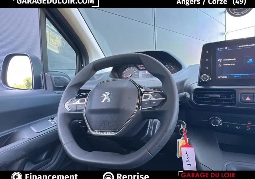 Vue intérieure centrée sur le volant Peugeot d’un Rifter bleu 2024 avec tableau de bord et écran tactile.