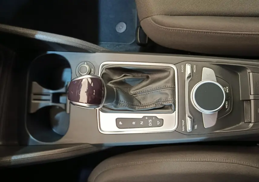 Vue plongeante sur la console centrale de l'Audi Q2 35 TFSI 2022, avec levier de vitesses automatique et molette de contrôle multimédia.