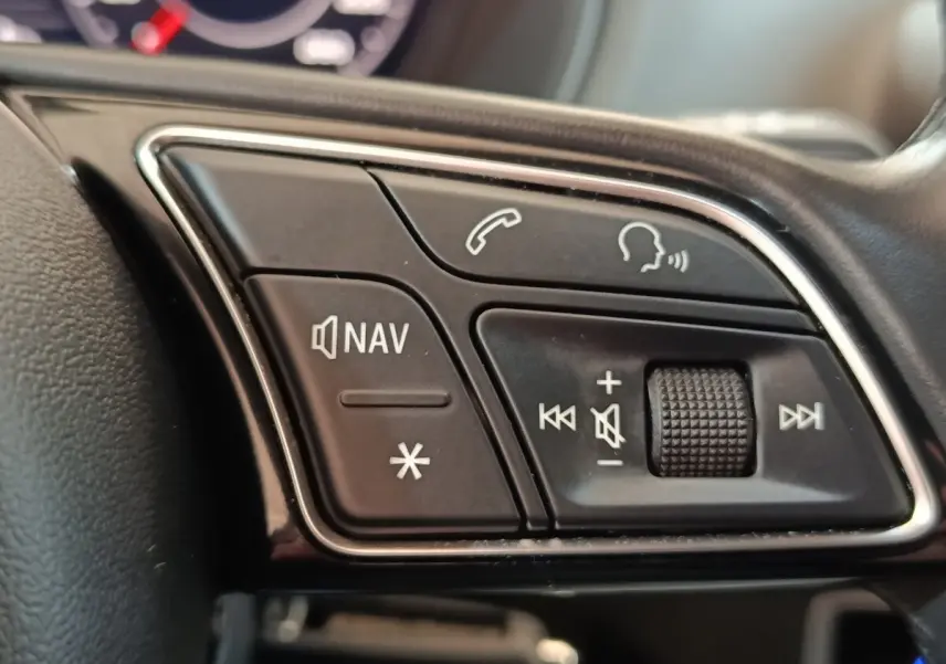 Gros plan sur les commandes audio et navigation au volant cuir noir de l'Audi Q2 35 TFSI 2022.