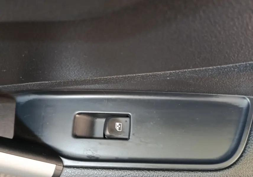 Gros plan sur l'interrupteur de commande de lève-vitre côté conducteur de l'Audi Q2 gris foncé 2022.