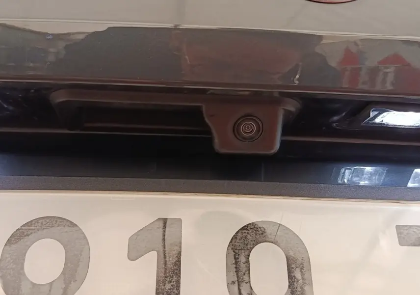 Gros plan sur la caméra de recul et l’éclairage de plaque arrière d’un Audi Q2 gris foncé.