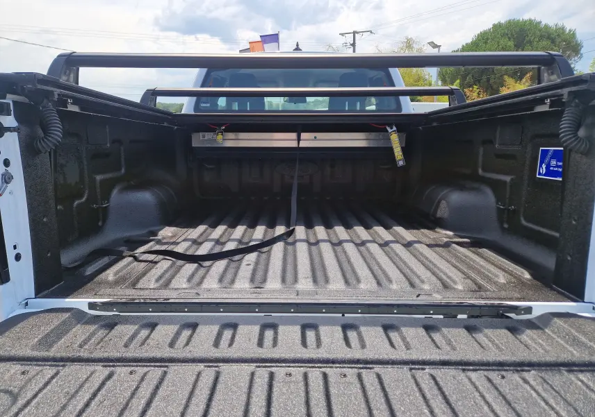 Vue arrière du plateau renforcé noir du Ford Ranger Super Cabine blanc avec rideau rigide coulissant et barres de protection.