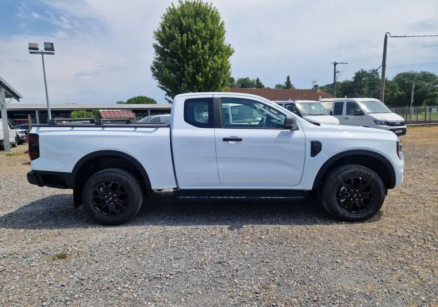 Vue de profil côté gauche d'un Ford Ranger Super Cabine blanc avec barres de toit et jantes noires.