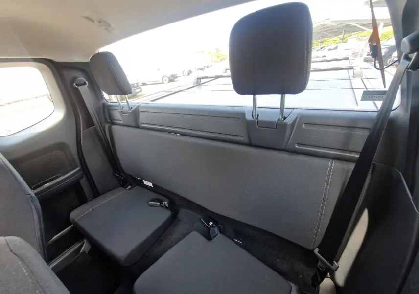Vue intérieure arrière du Ford Ranger Super Cabine blanc, montrant les sièges arrière rabattus et les appuie-têtes noirs.