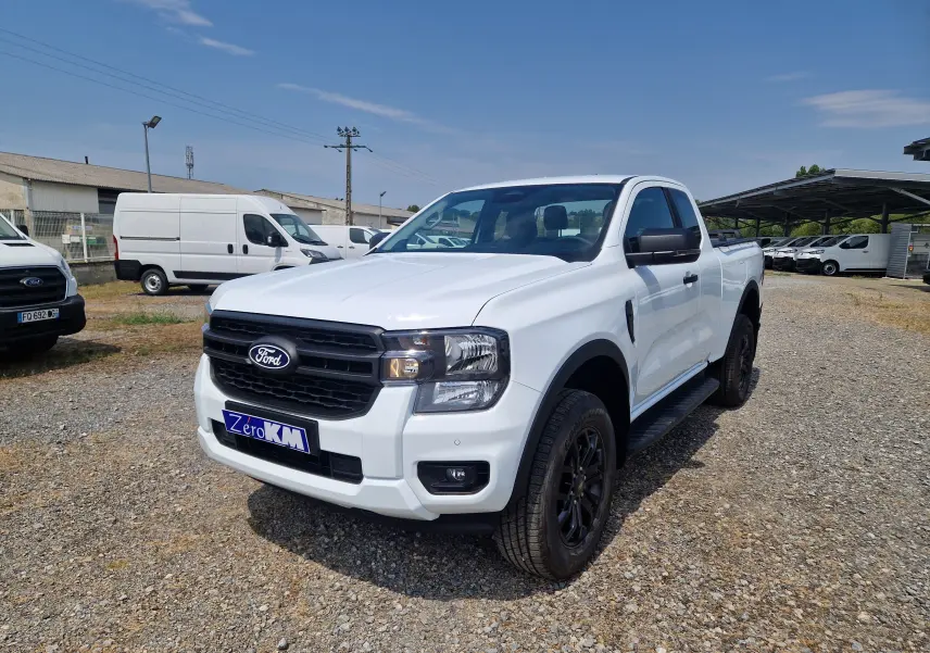 Ford Ranger Super Cabine blanc vu en 3/4 avant droit, avec calandre noire et marchepieds latéraux noirs.
