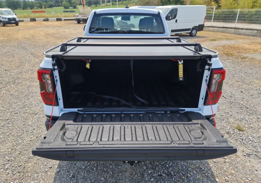 Vue arrière d'un Ford Ranger Super Cabine blanc avec plateau ouvert et rideau rigide coulissant visible.
