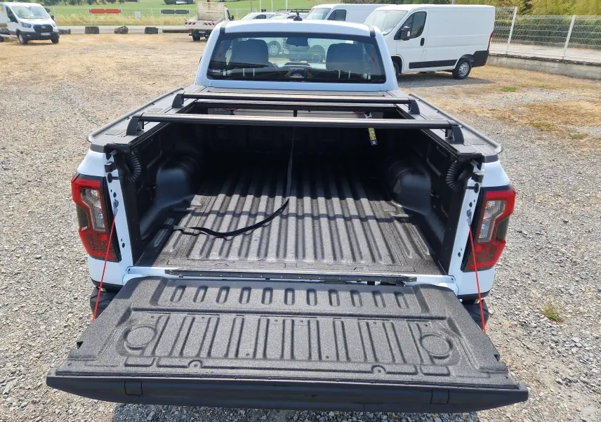 Vue arrière d’un Ford Ranger Super Cabine blanc avec plateau ouvert, rideau rigide coulissant et protection renforcée.