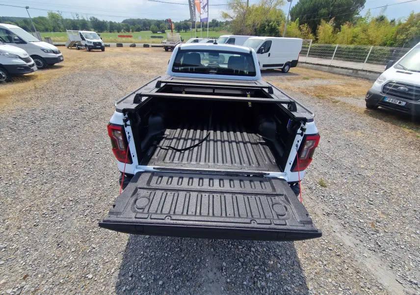 Vue arrière d’un Ford Ranger Super Cabine blanc avec plateau ouvert, rideau rigide coulissant et protection renforcée.