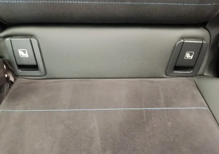 Détail de la banquette arrière en tissu gris foncé avec surpiqûres bleues et commandes de rabattement sur BMW X1 xDrive25e M Sport.