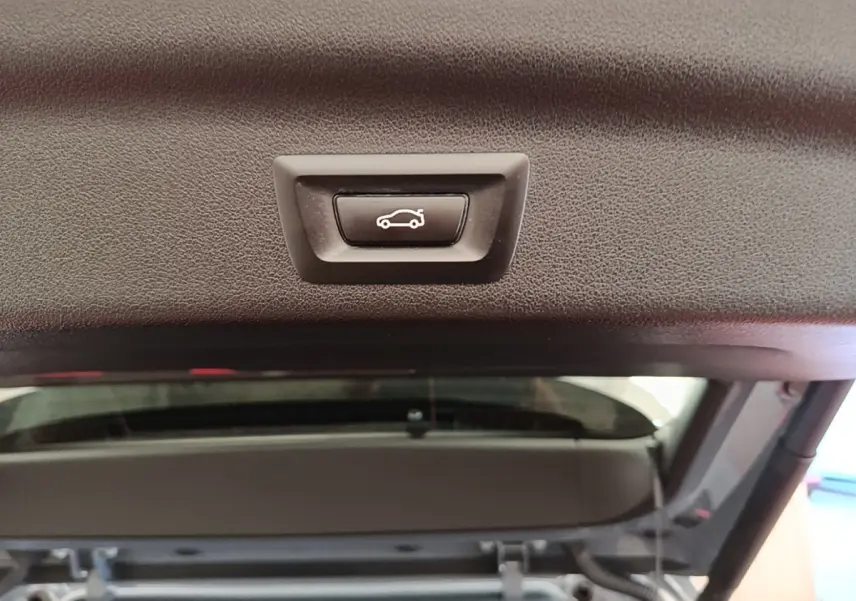Bouton d'ouverture électrique du coffre sur la partie intérieure du hayon d'un BMW X1 gris foncé 2023.
