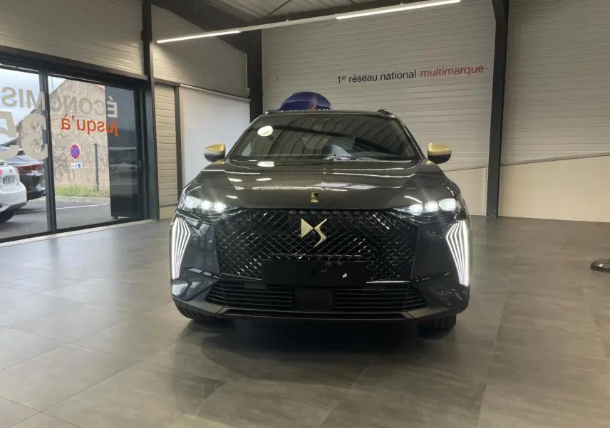 Vue avant d'un DS7 Crossback gris titanium avec calandre DS Wings noir brillant et feux LED verticaux allumés.