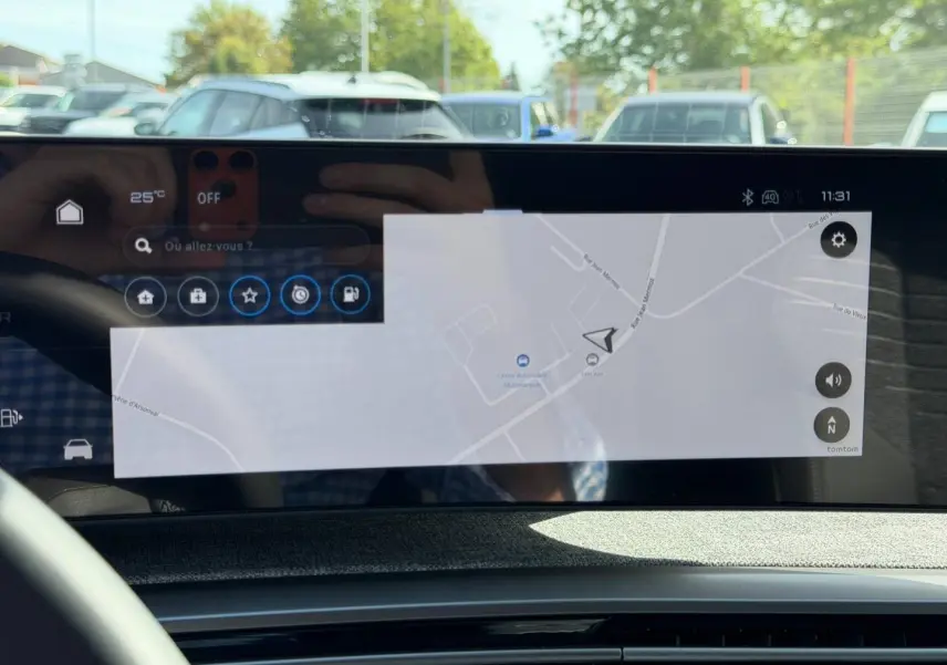 Écran tactile intérieur du Peugeot 3008 Hybrid 2026 affichant la navigation, avec reflet du volant et extérieur flou.