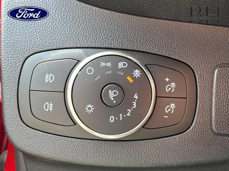 Gros plan sur le bouton de réglage des phares du Ford Puma rouge, avec commandes d'éclairage et intensité lumineuse.