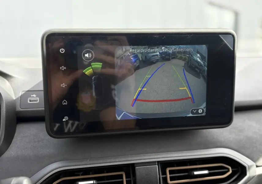 Écran tactile intérieur montrant la caméra de recul du Dacia Jogger Gris Schiste avec lignes de guidage colorées.