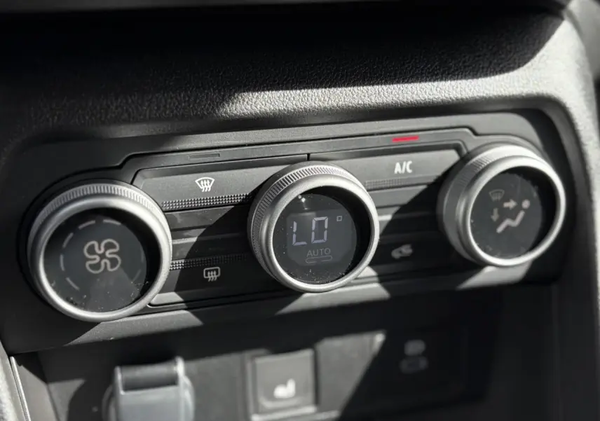 Gros plan sur les commandes de climatisation automatique du Dacia Jogger Gris Schiste, affichage digital au centre.