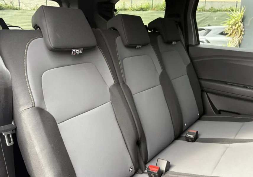 Vue intérieure sur la banquette arrière grise du Dacia Jogger 2025, avec appuie-têtes et ceintures visibles côté droit.