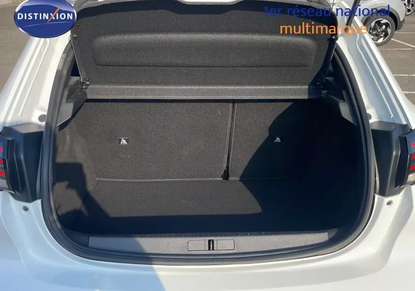 Coffre ouvert vu de l'arrière d'une Peugeot 208 blanc banquise, montrant l'espace de chargement vide et propre.