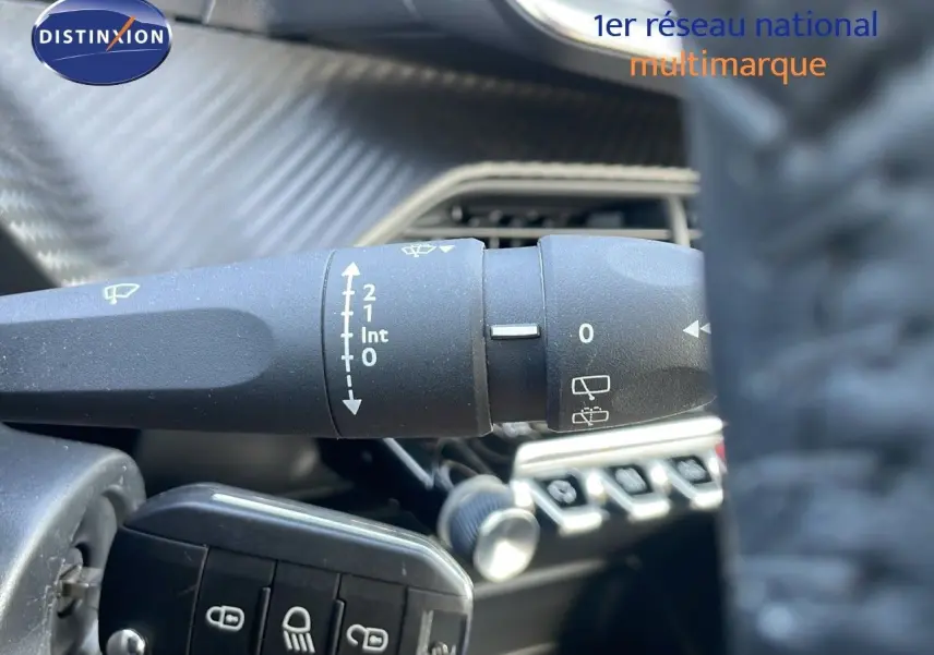 Gros plan sur la commande des essuie-glaces dans l'habitacle de la Peugeot 208 blanche, avec tableau de bord en arrière-plan.