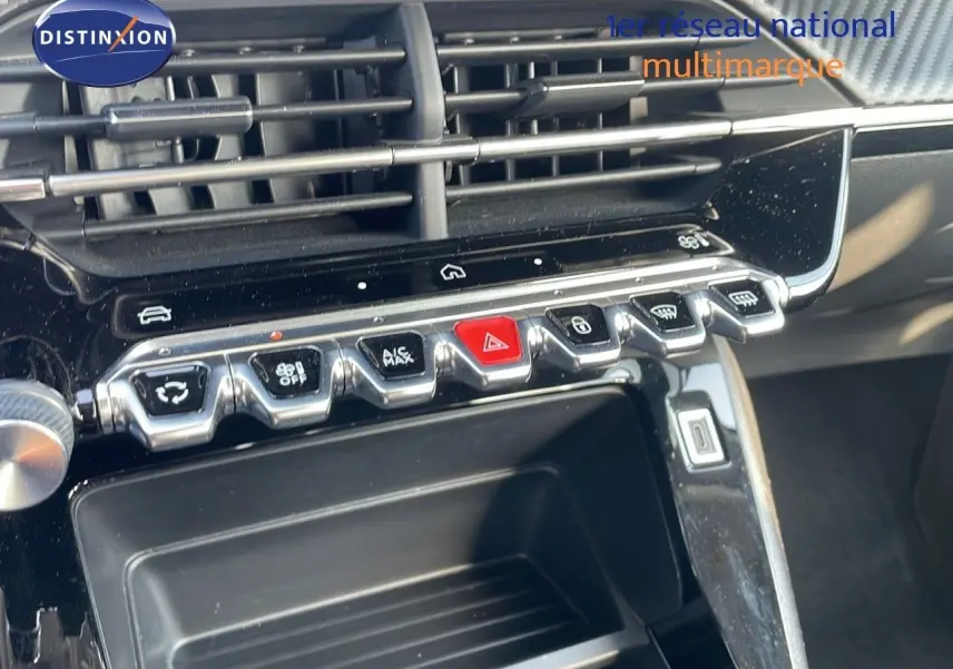 Gros plan sur la console centrale de la Peugeot 208 blanche, montrant les boutons de commande et les aérateurs.