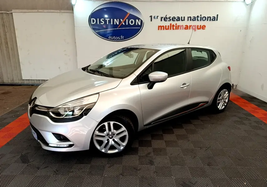 Renault Clio Business TCe 90 gris clair vue 3/4 avant droit en intérieur sur sol damier noir et orange.