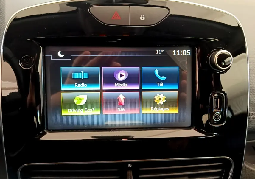 Écran tactile central allumé de la Renault Clio Business gris clair, affichant menu radio, média, téléphone, navigation et réglages.