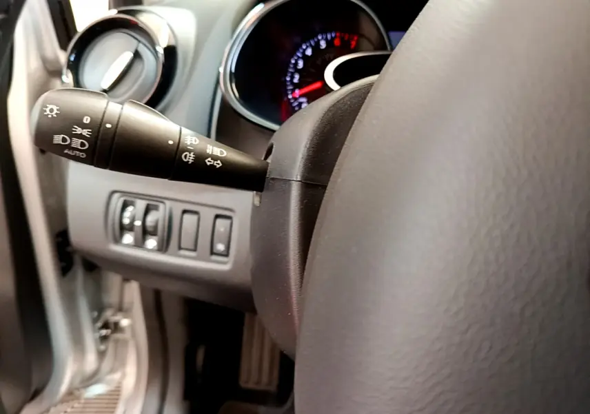 Gros plan sur la manette des phares à gauche du volant cuir dans l’habitacle gris clair de la Renault Clio Business TCe 90 2019.